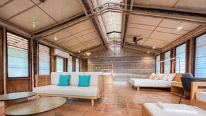 Une pièce spacieuse avec un plafond haut, un mur en briques et une grande fenêtre. On y trouve un canapé, un lit et une table.