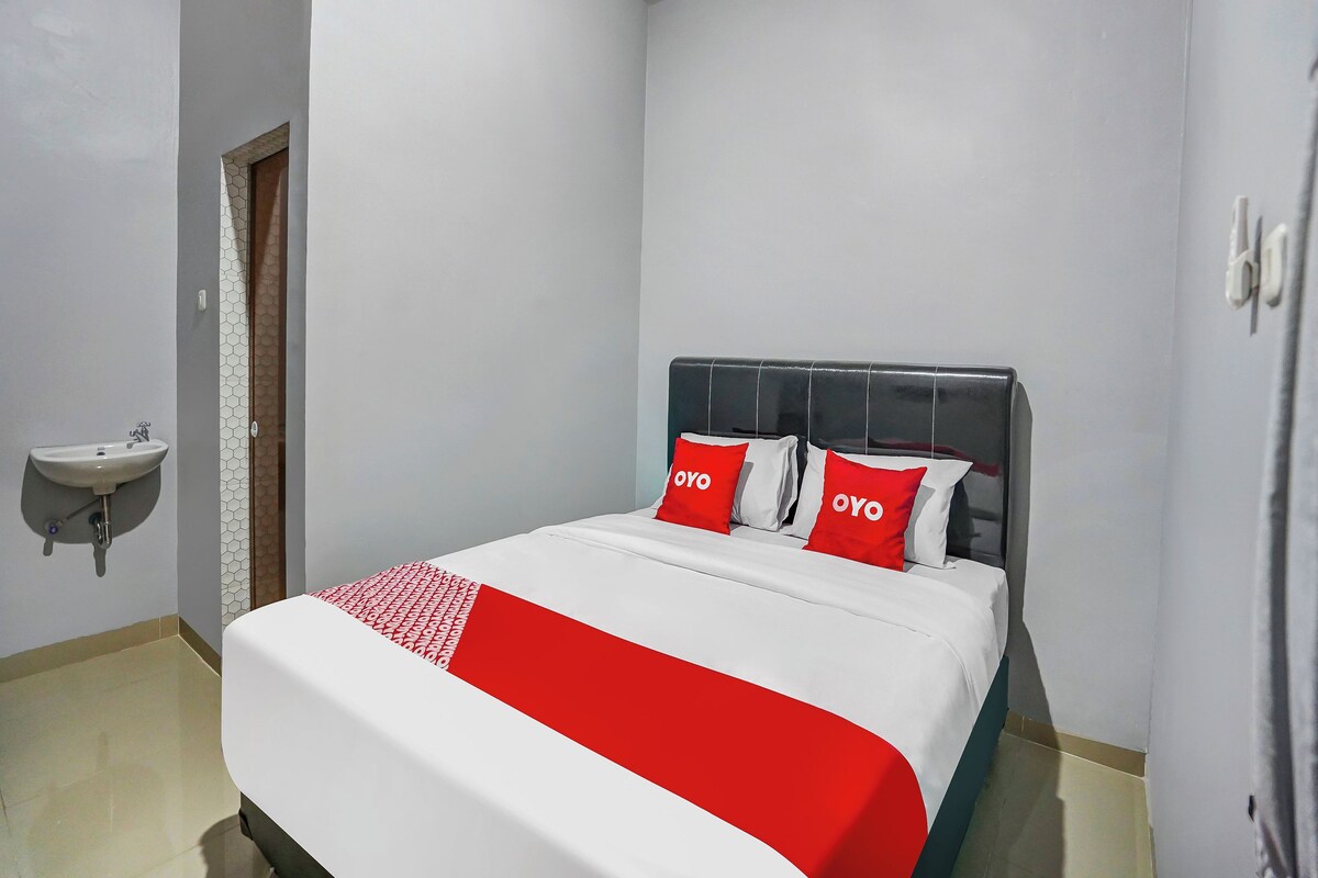 Une chambre à coucher comprenant un lit, une table de chevet, un lavabo fixé au mur et une porte ornée d’un motif hexagonal.
