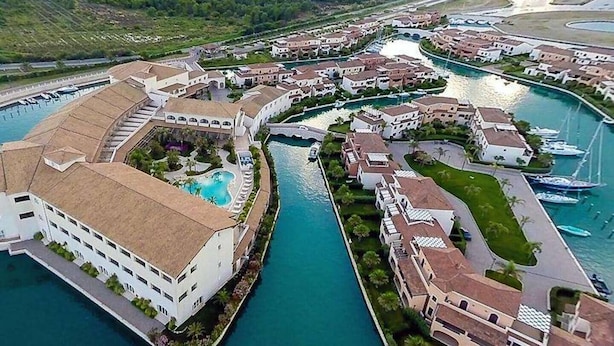 Un resort con piscina centrale collegato a una marina con imbarcazioni.