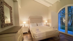 Una camera da letto con un letto grande, due comodini con lampade, una cassettiera e un'ampia finestra ad arco.