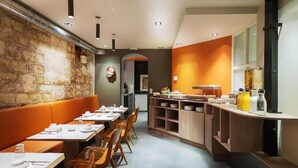 A restaurant with a long counter, wooden chairs, and tables set for dining. - Hotel Chateaudun Opera (Paris)