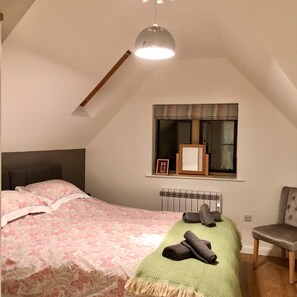 A bedroom with a bed, a chair, a window with a view, and a hanging light fixture.