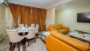 Un comedor con una mesa redonda y sillas, un sofá y un televisor montado en la pared.