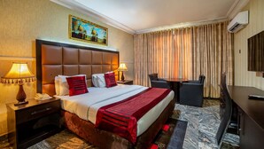 Una habitación de hotel con una cama grande, dos mesitas de noche con lámparas, un escritorio y una silla.