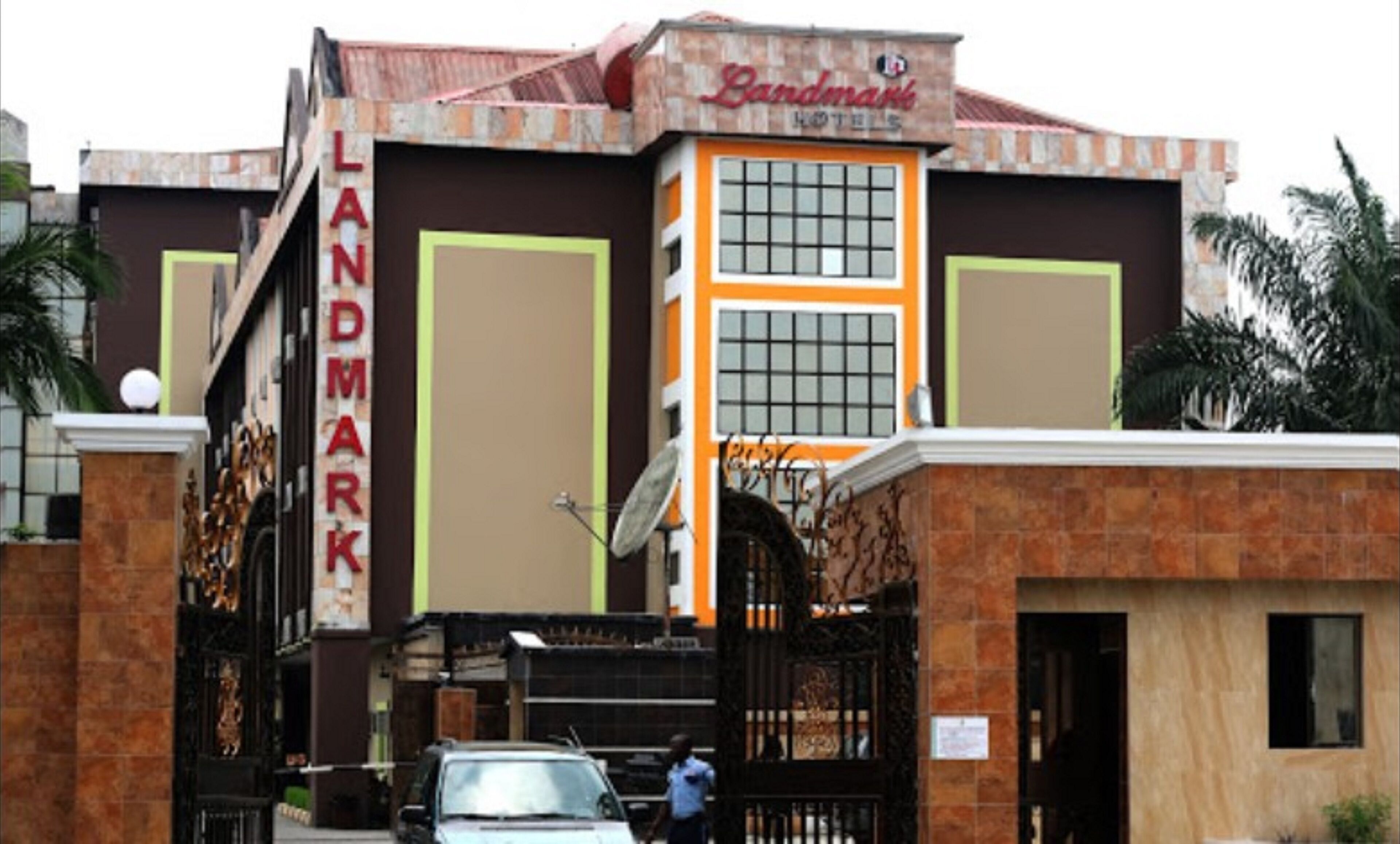 Un hotel llamado Landmark con fachada de ladrillo, ventanas grandes y una entrada protegida por una reja.