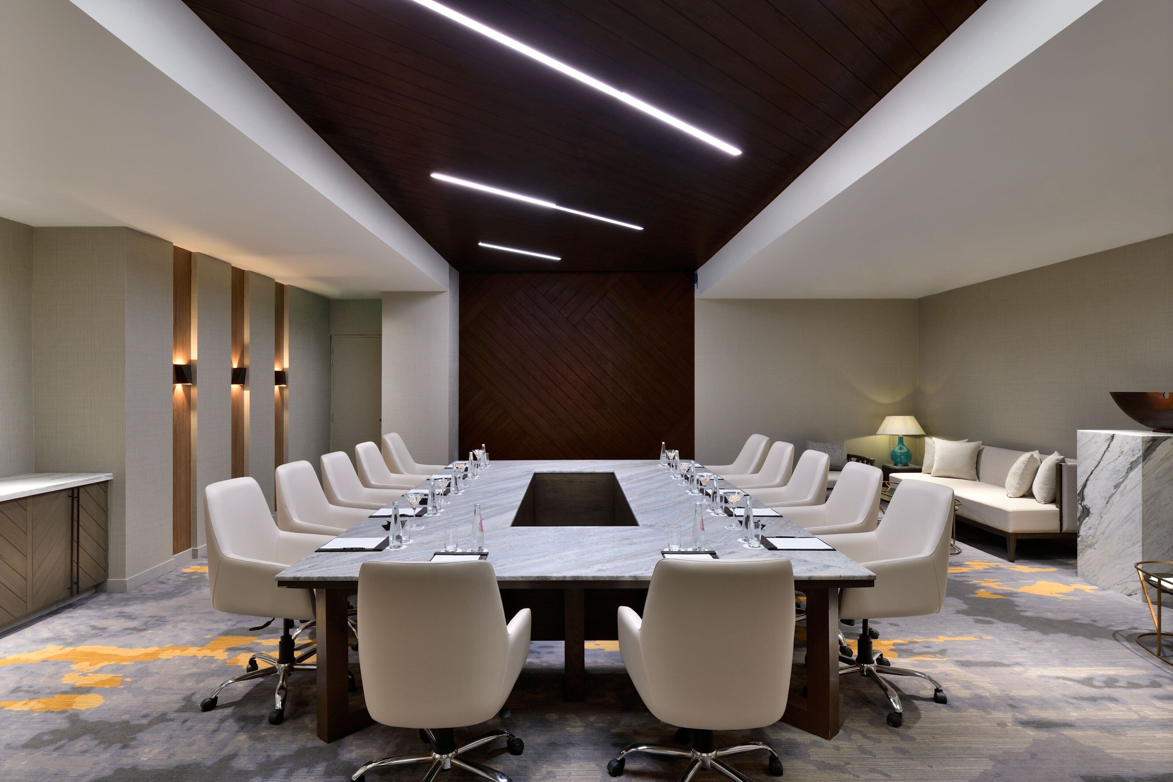 Un salón de conferencias con una larga mesa, varias sillas y un revestimiento de madera en la pared.