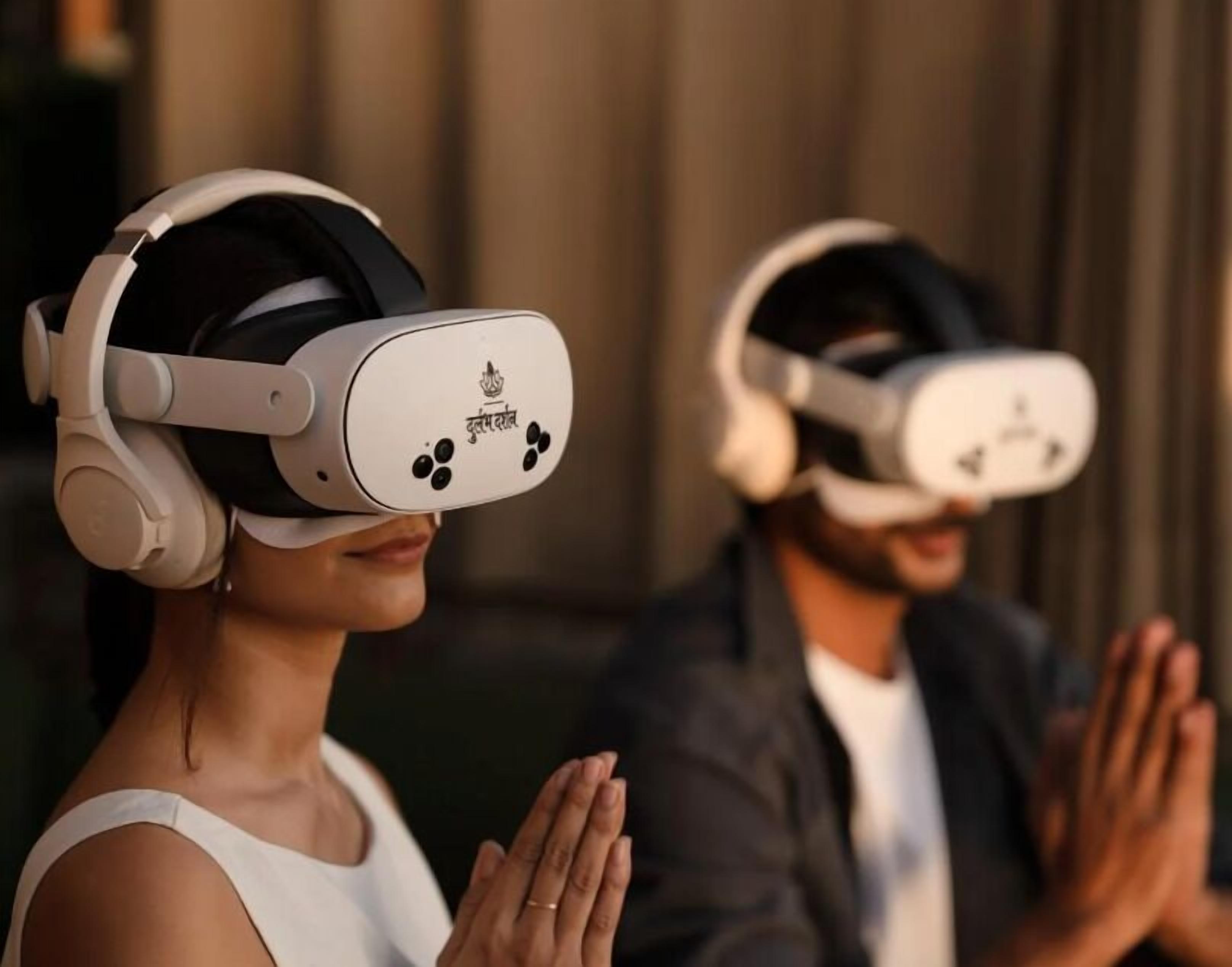 Two people wearing VR headsets, one in a white top and the other in a dark jacket, with their hands in a praying position.