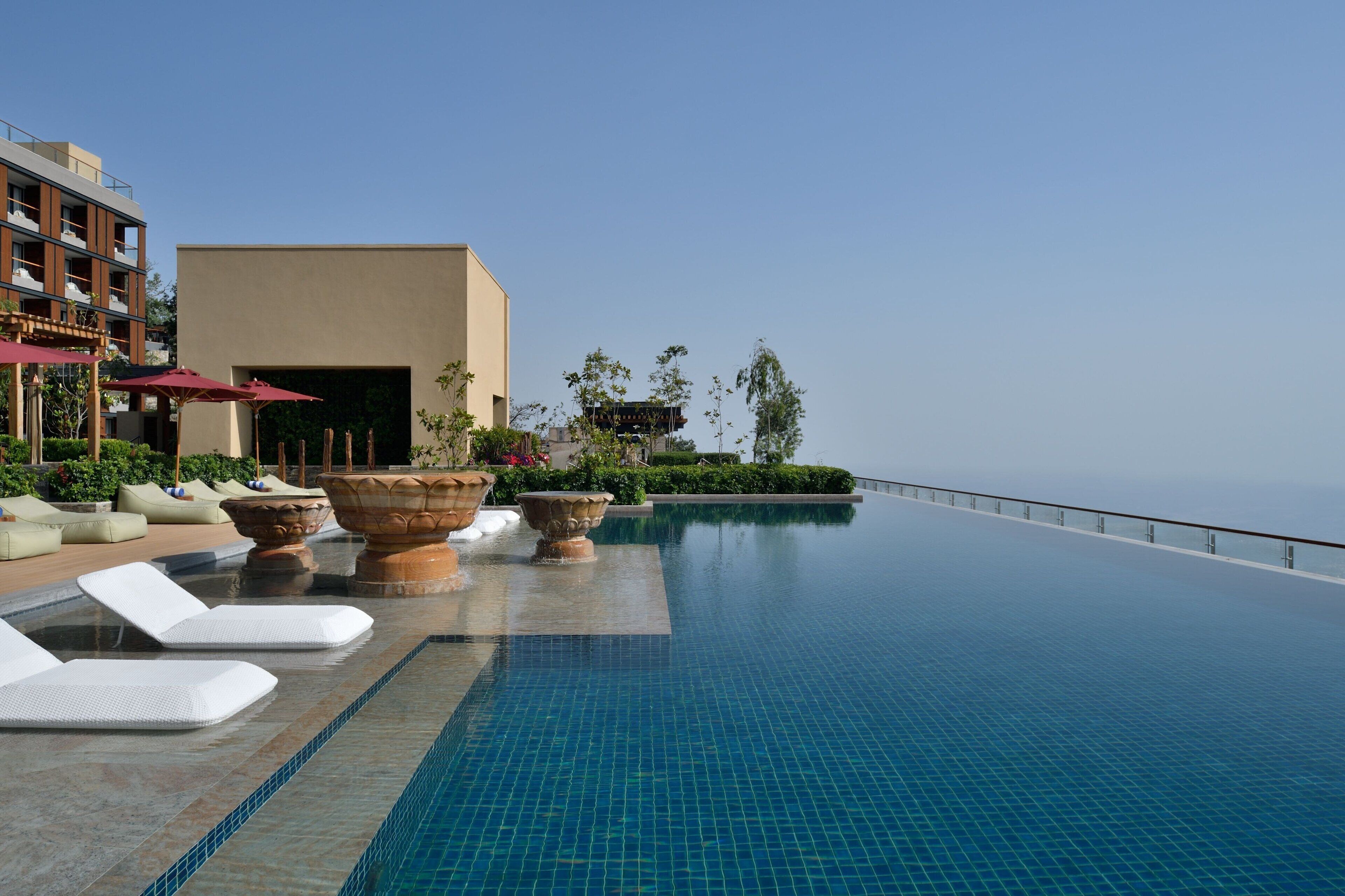 A poolside area with lounge chairs, large planters, and a view of the sea.