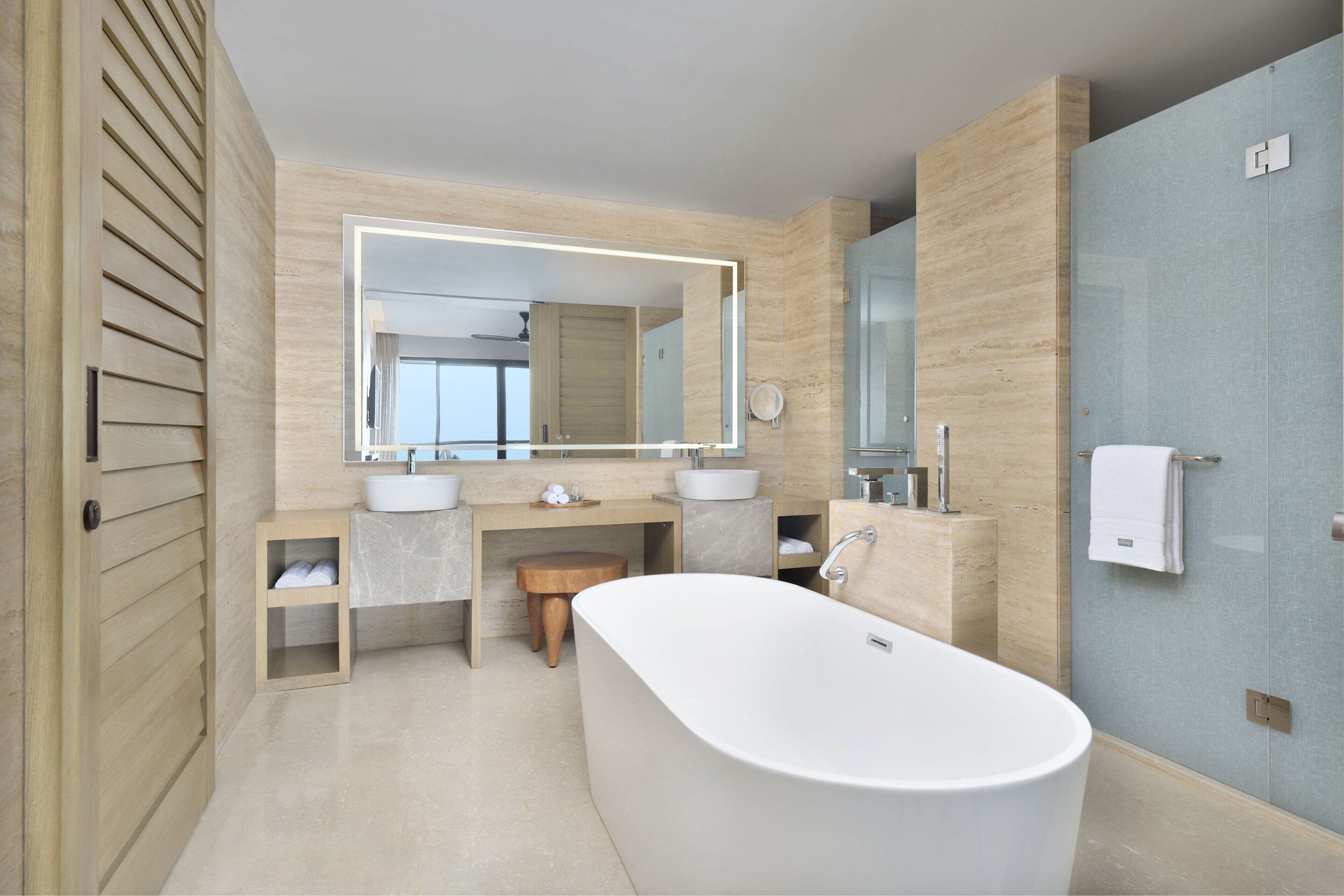 Ein modernes Badezimmer mit einer freistehenden Badewanne, zwei Waschbecken, einem großen Spiegel und einer Holzanrichte.