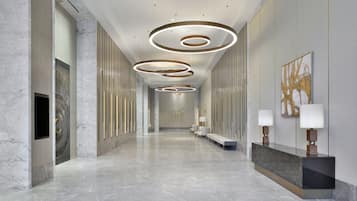 Una hall d'hotel moderna con pavimento in marmo, luci a soffitto circolari e una reception con lampade.