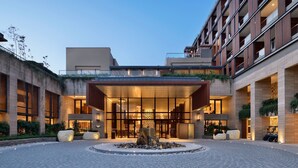 Una entrada de hotel moderna con una característica central de roca, un patio interior y una fachada bien iluminada.