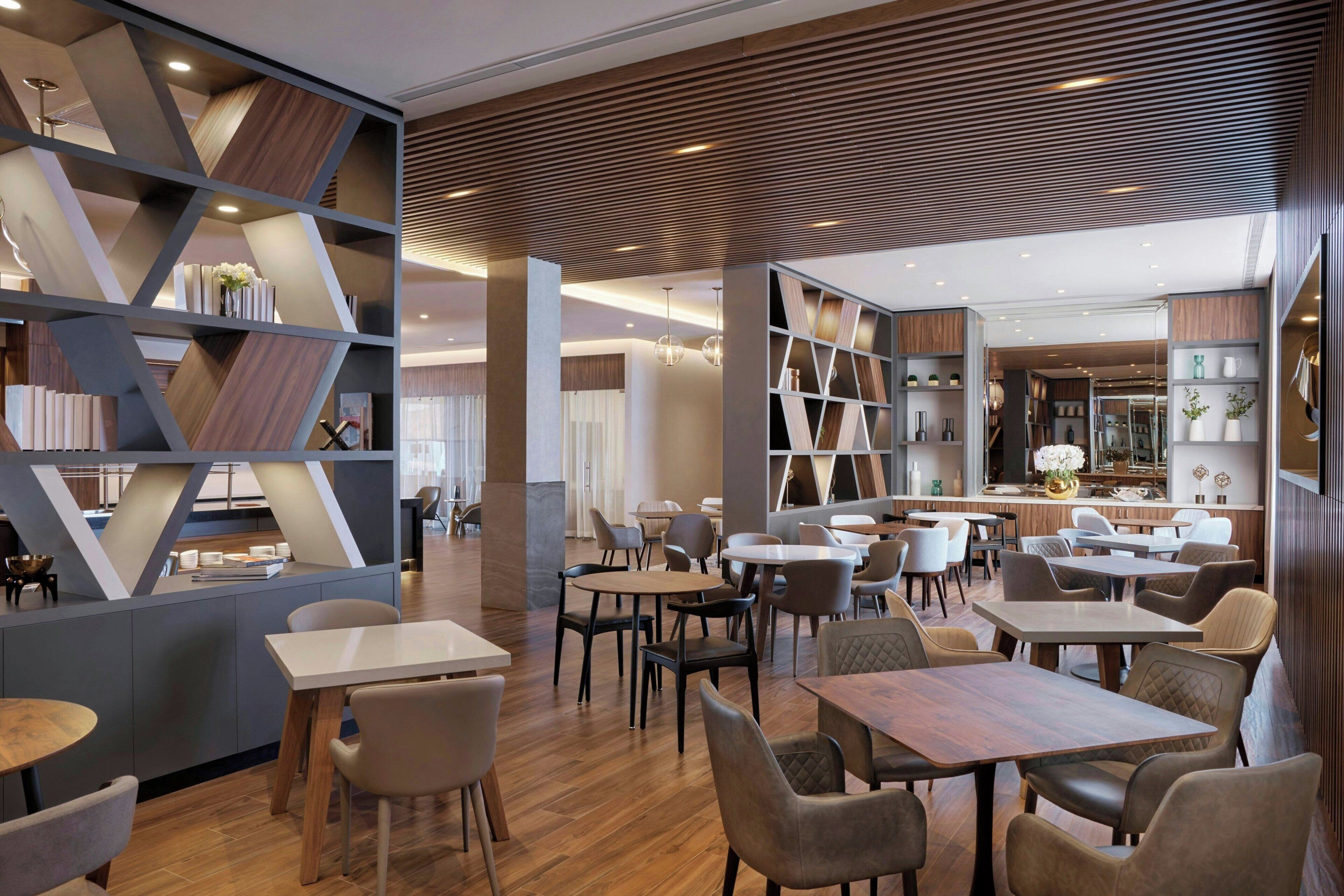 Um restaurante moderno com piso de madeira, diversas áreas de estar e um balcão central.