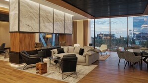 A modern living room with a large window, a sofa, a coffee table, and a TV.