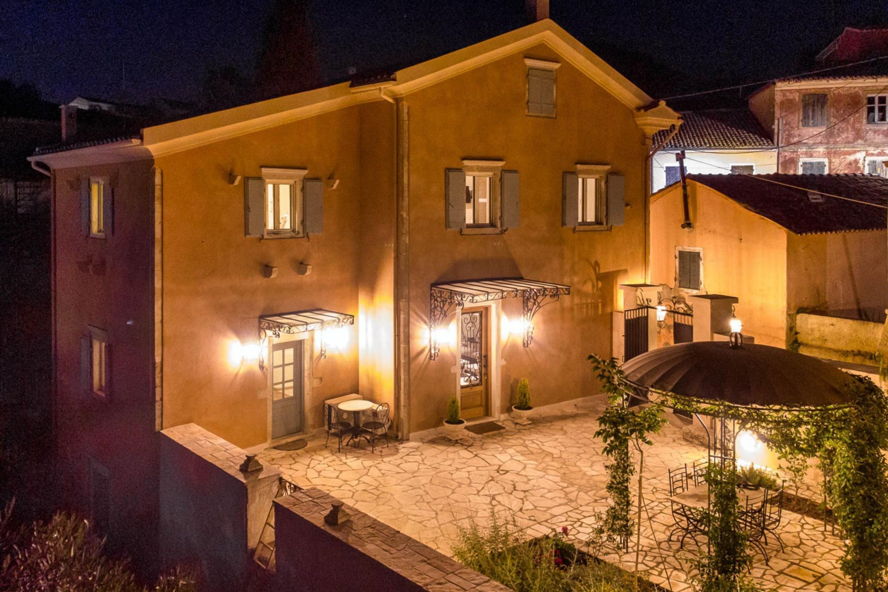 A two-story building with a stone-paved courtyard, a covered outdoor seating area, and a well-lit entrance.