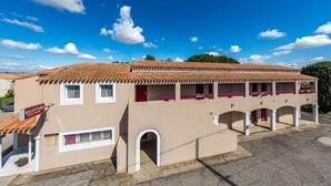 Un hotel con recepción, varios balcones y un techo de tejas.