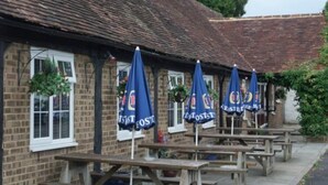 Un pub traditionnel avec une terrasse et des parasols bleus.