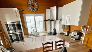 A cozy kitchen with wooden cabinets, a stove, and a dining table with chairs.