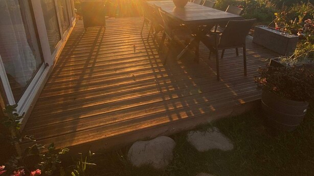 A wooden deck with a table and chairs, overlooking a scenic landscape with a sunset.