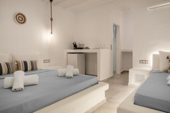 A hotel room with two beds, a small desk, and a light fixture.
