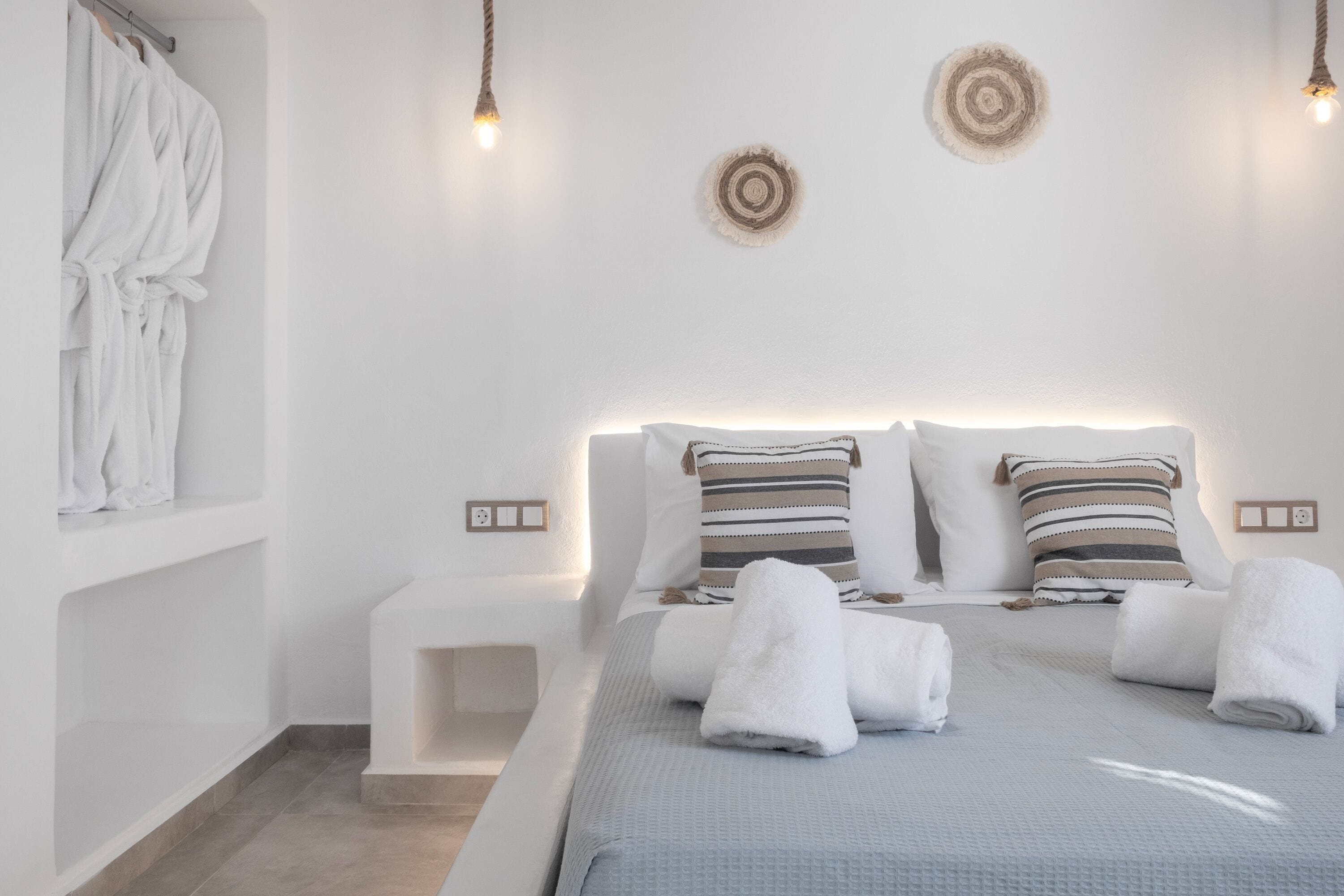 A modern bedroom with a bed, two bedside tables, and a robe hanging on a rack.