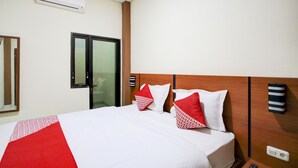 Een hotelkamer met een bed, een spiegel, een deur en een wandairconditioner.