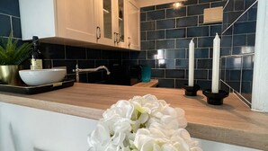 A modern kitchen with dark blue tiles, white cabinets, and a wooden countertop. - Mango Estudio!! Piscina!! Playa a 150m!! (Torrox)