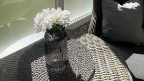 A room with a large window, a wicker chair, a black cushion, and a vase with white flowers. - Mango Estudio!! Piscina!! Playa a 150m!! (Torrox)