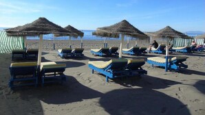 A beach with sun loungers and thatched umbrellas. - Mango Estudio!! Piscina!! Playa a 150m!! (Torrox)