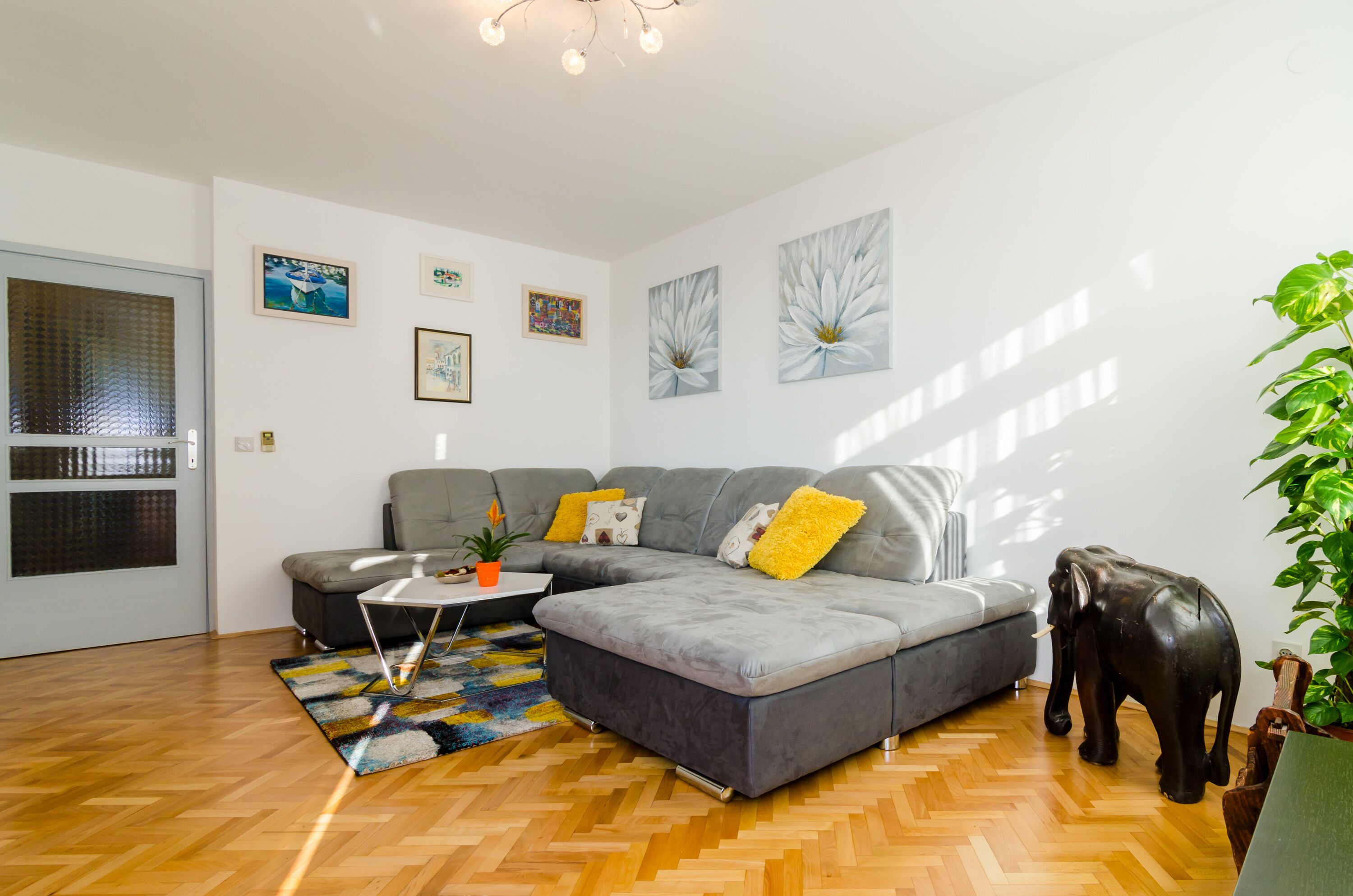 Una sala de estar moderna con un sofá seccional gris, una mesa de centro y una estatua decorativa de un elefante.