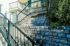 Staircase leads to a traditional building with stonework and greenery.