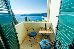 Enjoy a serene sea view from this balcony, featuring a chair and table for a relaxing moment.