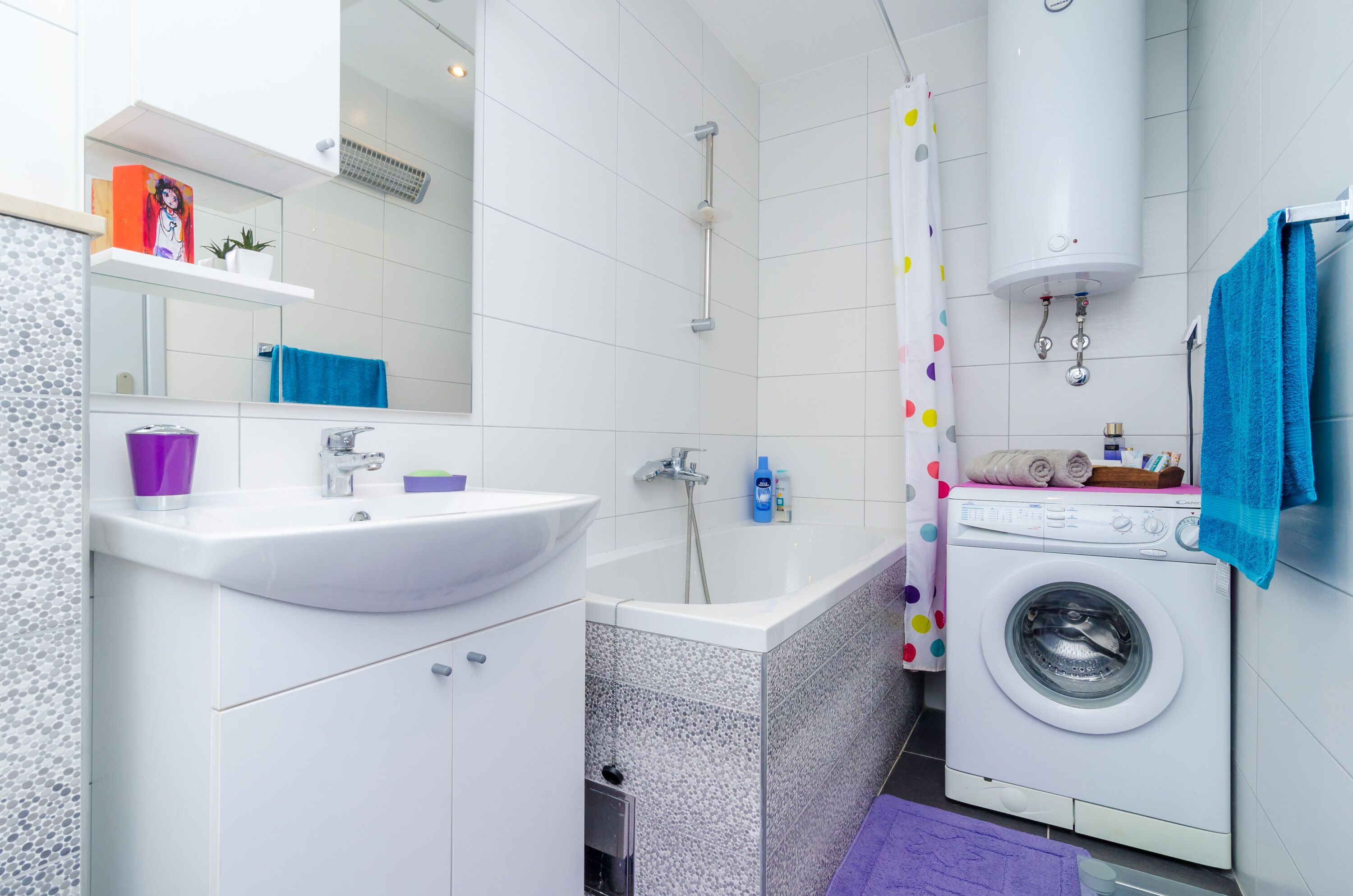Ein modernes Badezimmer mit Waschbecken, Dusche und Waschmaschine.