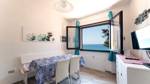 A room with a table, chairs, a desk, a computer, and a window with a view of the sea. - Fantastic Seaview Turquoise House (Santa Margherita di Pula)