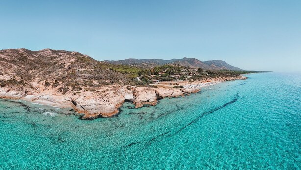A coastal landscape with clear turquoise waters, rocky cliffs, and distant mountains. - Fantastic Seaview Turquoise House (Santa Margherita di Pula)