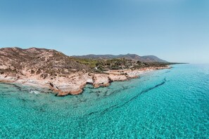Een kustlandschap met helder turquoise water, rotsachtige kliffen en verre bergen.