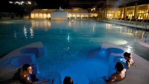 A pool with three people in the water, a covered area with seating, and a building with lights in the background. - RED APARTMENT in Poggio alla Cavalla farmhouse in the heart of Tuscany (Toscana)