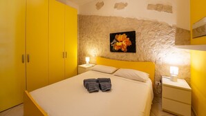 A room with a bed, a nightstand, a lamp, and a painting on the wall. - Yellow House with garden, 130 meters from the beach (Santa Margherita di Pula)