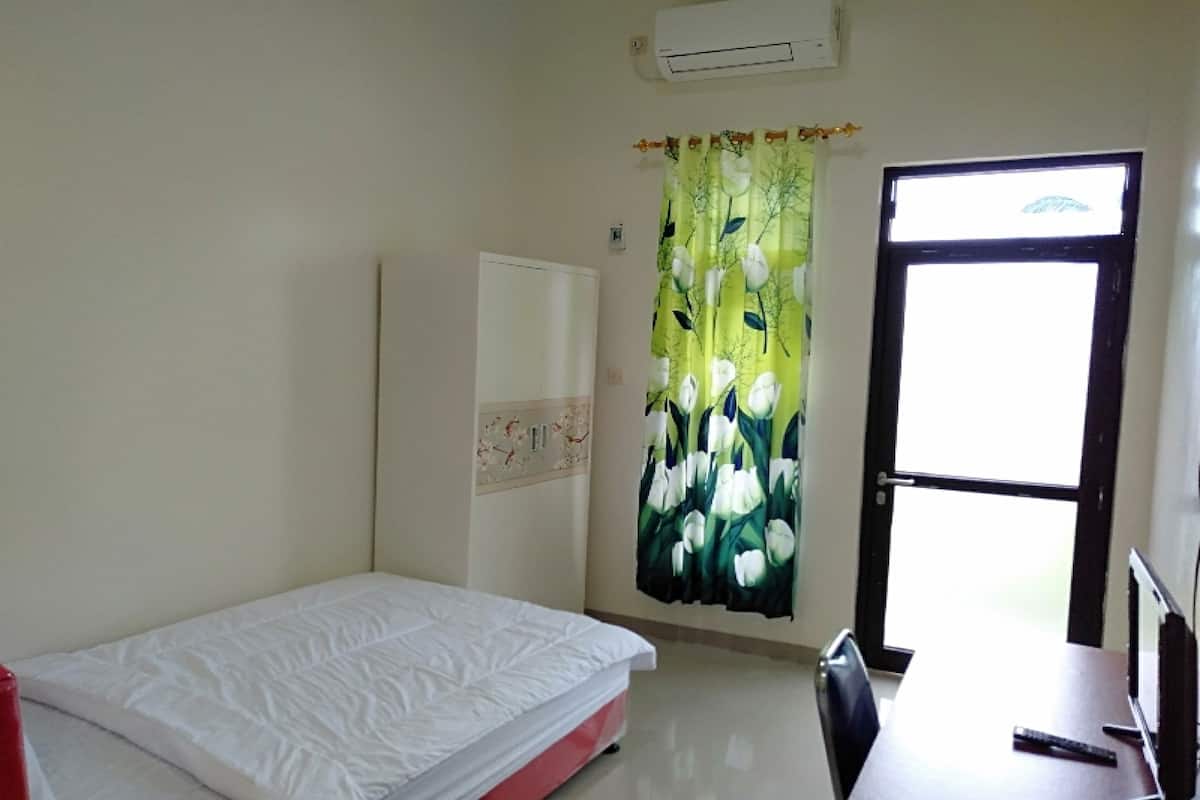 Ein Zimmer mit Bett, Schreibtisch, Stuhl, Tür und Fenster.