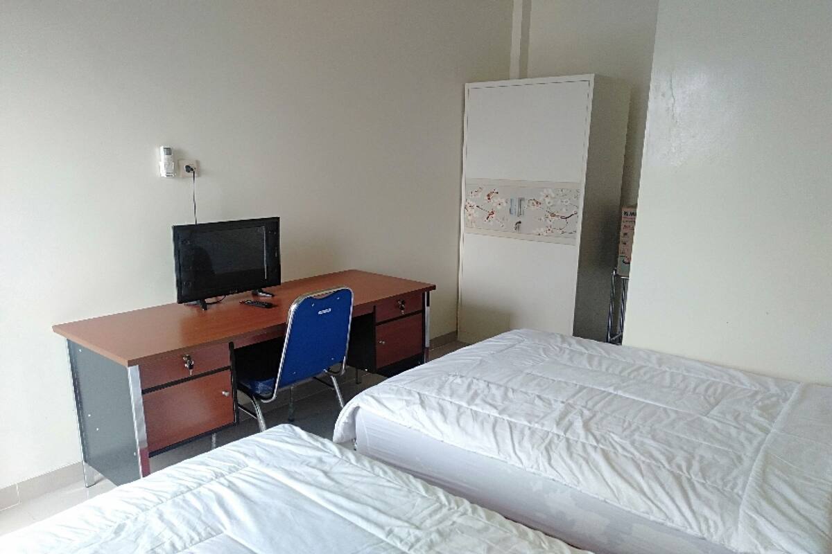 Ein Zimmer mit Schreibtisch, Stuhl, Bett und Kleiderschrank.