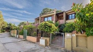 A two-story house with a stone facade, a gated entrance, and a small garden area. - Blue House, 300 meters from the beach (Santa Margherita di Pula)