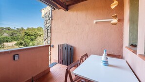A balcony with a white table, a blue vase, and a spiral light fixture. - Blue House, 300 meters from the beach (Santa Margherita di Pula)