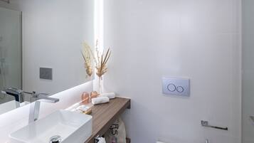 A modern bathroom with a white sink, wooden countertop, and a toilet.