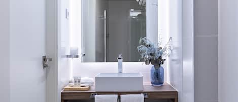 Un baño moderno con lavamanos, espejo y toallero blancos.