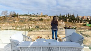 A terrace with white wicker furniture, a clear view of the surrounding landscape, and a person standing in the background. - La Casa de las Flores  (Cartagena)