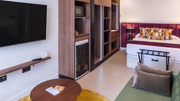 Una sala de estar moderna con televisor de pantalla plana, sofá, mesa de centro y una cocina integrada con lavavajillas.