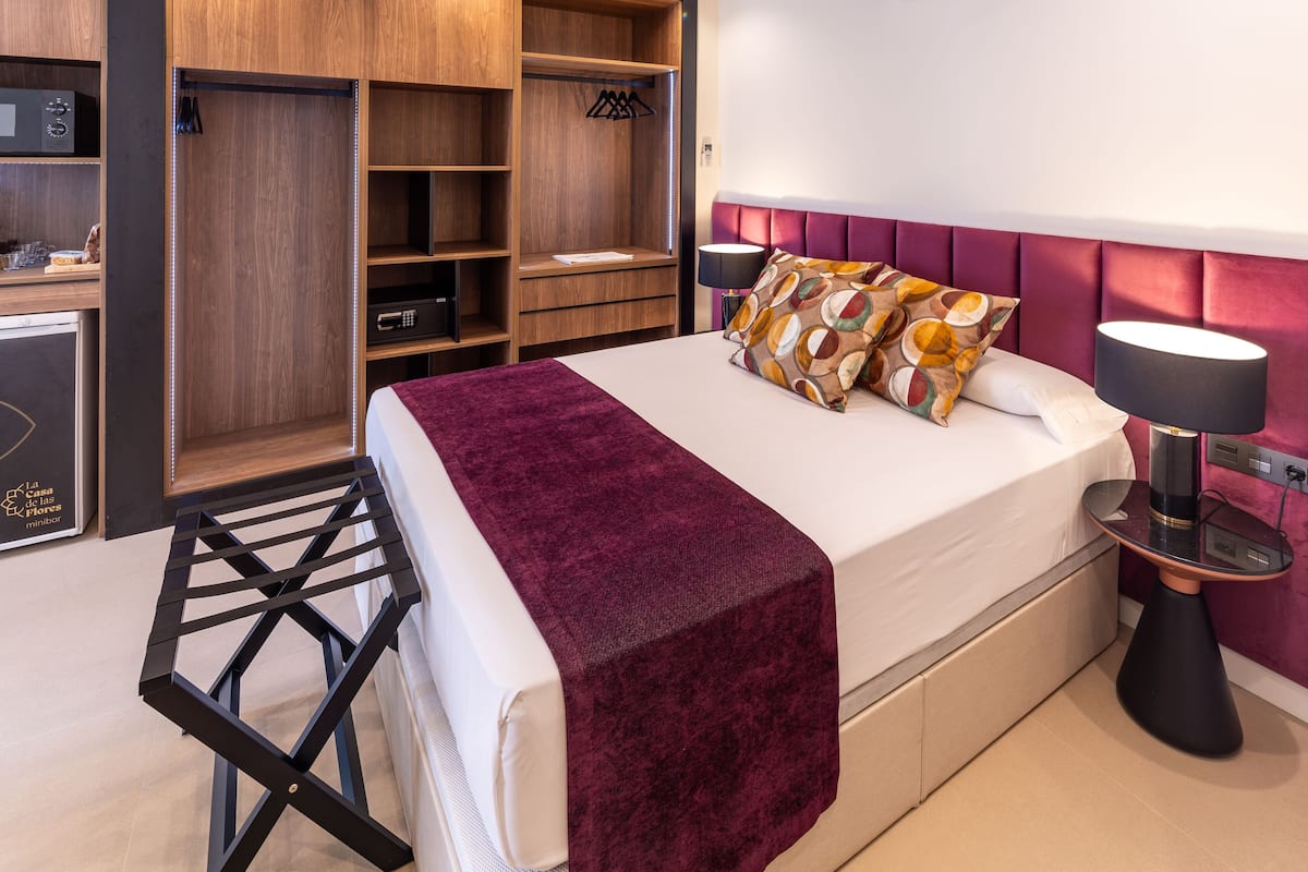 A modern bedroom with a bed, a wardrobe, a desk, and an air conditioning unit.