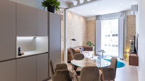 A modern kitchen with built-in cabinets, a dining area with a glass table, and a living space with a sofa and a plant. - La Casa de las Flores  (Cartagena)
