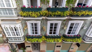 A building with multiple balconies, each with green railings and flower boxes. - La Casa de las Flores  (Cartagena)