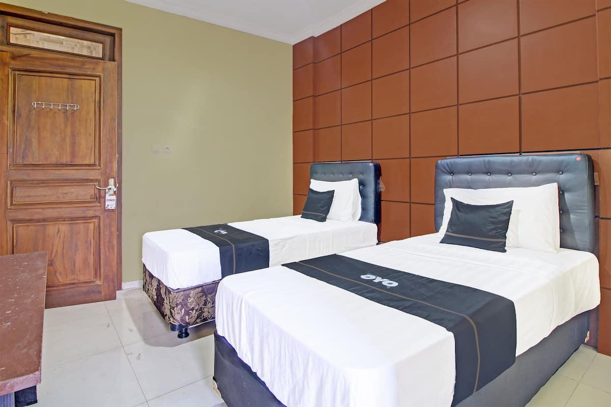 A hotel room with two beds, a wooden door, and a tiled floor.