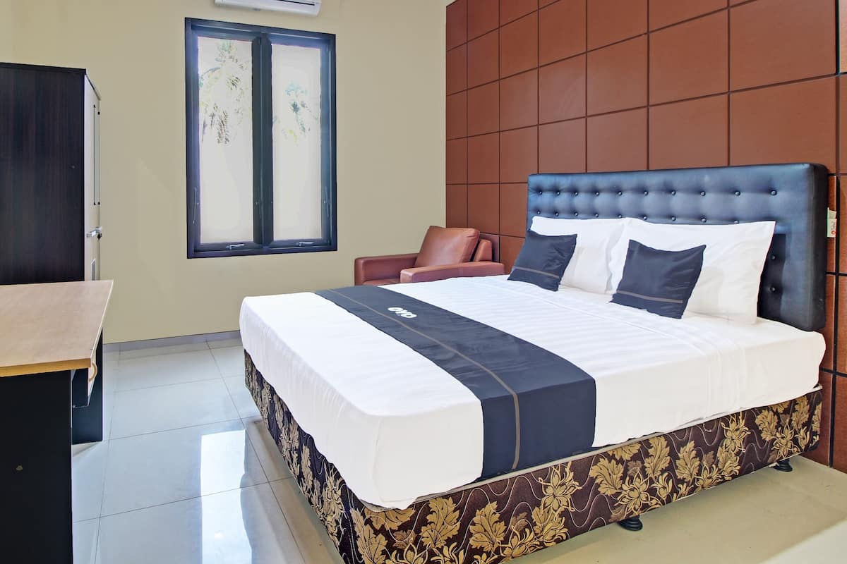 A neatly arranged hotel room with a large bed, a small desk, and a window with a view.